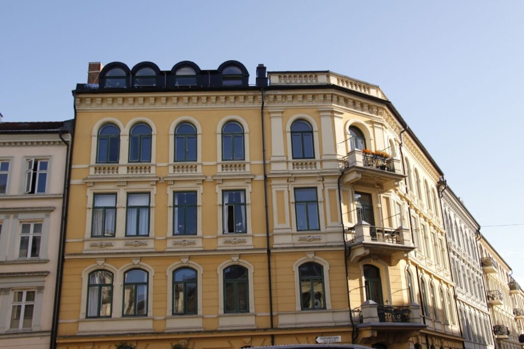 Gul bygård med klassiske vinduer og balkonger, fasaderehabilitering som bevarer historisk preg